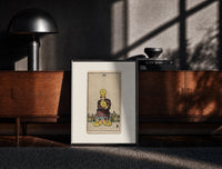 Black-framed Man clutching gold pentacle coins print on a moody console with designer coffee-table books