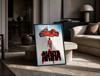 Akira red bike and rider framed anime poster on white print in a black frame leaning on a travertine table in a sunlit lounge