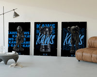 Black KAWS Companion framed poster set of 3 with blue script typography three-panel set displayed beside a brown leather sofa