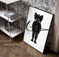 KAWS Chum figure with swoosh line framed poster on white poster in a black frame leaning beside a shelf in a raw-plaster loft