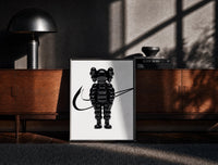 Black-framed KAWS Chum figure with swoosh line framed poster on white print on a moody console with designer coffee-table…
