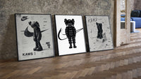 Black and white KAWS Nike framed poster set of 3 three-piece set leaning on parquet beside a vintage loft door