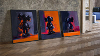 KAWS Companion framed poster set of 3 in orange and violet brushwork three-piece set leaning on parquet beside a vintage…