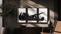 Reclining black KAWS Companion framed poster set of 3 with swoosh marks triptych in three walnut frames above a sideboard…