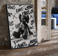 Sitting KAWS Companion framed poster print in a black frame leaning beside a vintage door on parquet