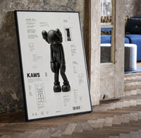 KAWS Companion technical spec sheet framed poster on cream print in a black frame leaning beside a vintage door on parquet