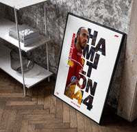 Lewis Hamilton 44 Ferrari red framed F1 poster with cut-out type poster in a black frame leaning beside a shelf in a…
