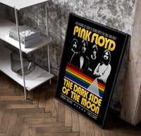 Pink Floyd vintage concert style framed poster with rainbow prism poster in a black frame leaning beside a shelf in a…