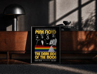 Black-framed Pink Floyd vintage concert style framed poster with rainbow prism print on a moody console with designer…