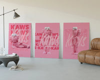 Pink furry KAWS Companion framed poster set of 3 three-panel set displayed beside a brown leather sofa