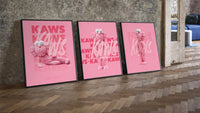 Pink furry KAWS Companion framed poster set of 3 three-piece set leaning on parquet beside a vintage loft door