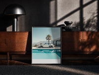 Black-framed Cream Porsche 911 poolside framed car poster with palms print on a moody console with designer coffee-table…