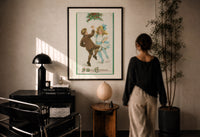 Frances Brundage Dancing Children print in a black frame on a sunlit plaster wall, a person looking on beside a mushroom lamp