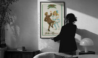 Frances Brundage Dancing Children print in a slim black frame being hung on a sunlit wall in a monochrome room