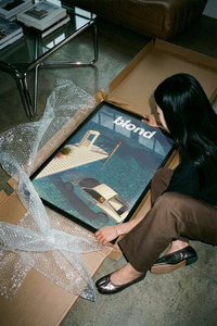 Close-up of a Blond art print being unrolled showing the sunken luxury car on a concrete surface