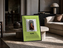 Man covering face album cover print in a black frame leaning on a travertine table in a sunlit lounge