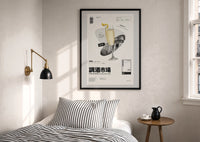 French 75 Cocktail Market print in a black frame above a bed with striped linens, a brass wall lamp and a sunlit window