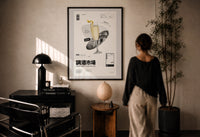 French 75 Cocktail Market print in a black frame on a sunlit plaster wall, a woman looking on beside a mushroom lamp