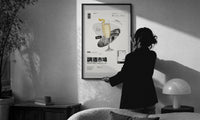 French 75 Cocktail Market print in a slim black frame being hung on a sunlit wall in a monochrome room