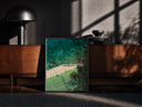 Black-framed Seaside tennis court by ocean print on a moody console with designer coffee-table books