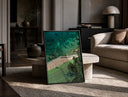 Seaside tennis court by ocean print in a black frame leaning on a travertine table in a sunlit lounge
