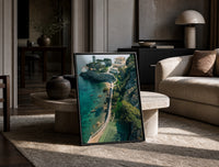 Cliffside coastal luxury villa estate print in a black frame leaning on a travertine table in a sunlit lounge