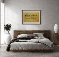 Vintage French perfume label print in a dark wood frame above a rattan bed on a plaster wall