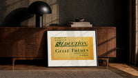 Vintage French perfume label print in a black frame leaning against a walnut console in lamplight