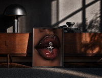 Black-framed Glossy Lips with a Silver Charm print on the floor in front of a dark wooden console