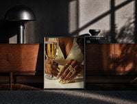 Black-framed Gold Nails and a Stemmed Glass print on the floor in front of a dark wooden console
