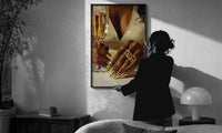 Gold Nails and a Stemmed Glass print in a slim black frame being hung on a sunlit wall in a monochrome room
