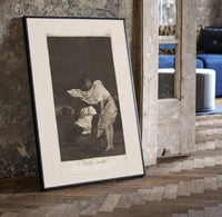 Woman battling wind in cloak print in a black frame leaning beside a vintage door on parquet
