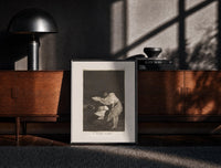 Black-framed Woman battling wind in cloak print on a moody console with designer coffee-table books