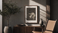 Woman battling wind in cloak poster framed above a fluted sideboard beside an olive tree