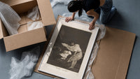 Woman battling wind in cloak framed print being unpacked from protective bubble wrap and a box