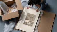 Winged figures and bird-people above sleeping women framed print being unpacked from protective bubble wrap and a box