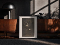 Black-framed Nightmarish figures with grotesque faces print on a moody console with designer coffee-table books