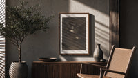 Nightmarish figures with grotesque faces poster framed above a fluted sideboard beside an olive tree