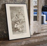 grotesque devils and figures with book print in a black frame leaning beside a vintage door on parquet