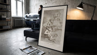 grotesque devils and figures with book print in a slim black frame leaning on a dark sofa in a concrete print studio