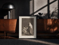 Black-framed Mother with children fearing hooded figure print on a moody console with designer coffee-table books