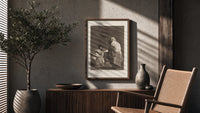 Mother with children fearing hooded figure poster framed above a fluted sideboard beside an olive tree