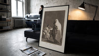 Mother with children fearing hooded figure print in a slim black frame leaning on a dark sofa in a concrete print studio