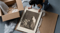 Mother with children fearing hooded figure framed print being unpacked from protective bubble wrap and a box