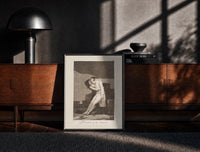 Black-framed man embracing dying woman print on a moody console with designer coffee-table books