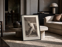 man embracing dying woman print in a black frame leaning on a travertine table in a sunlit lounge