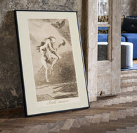 Two witches flying on a broom print in a black frame leaning beside a vintage door on parquet