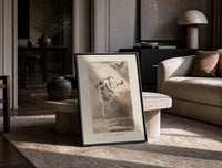 Two witches flying on a broom print in a black frame leaning on a travertine table in a sunlit lounge
