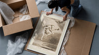 Two witches flying on a broom framed print being unpacked from protective bubble wrap and a box