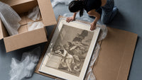 Sleeping man surrounded by owls and bats framed print being unpacked from protective bubble wrap and a box